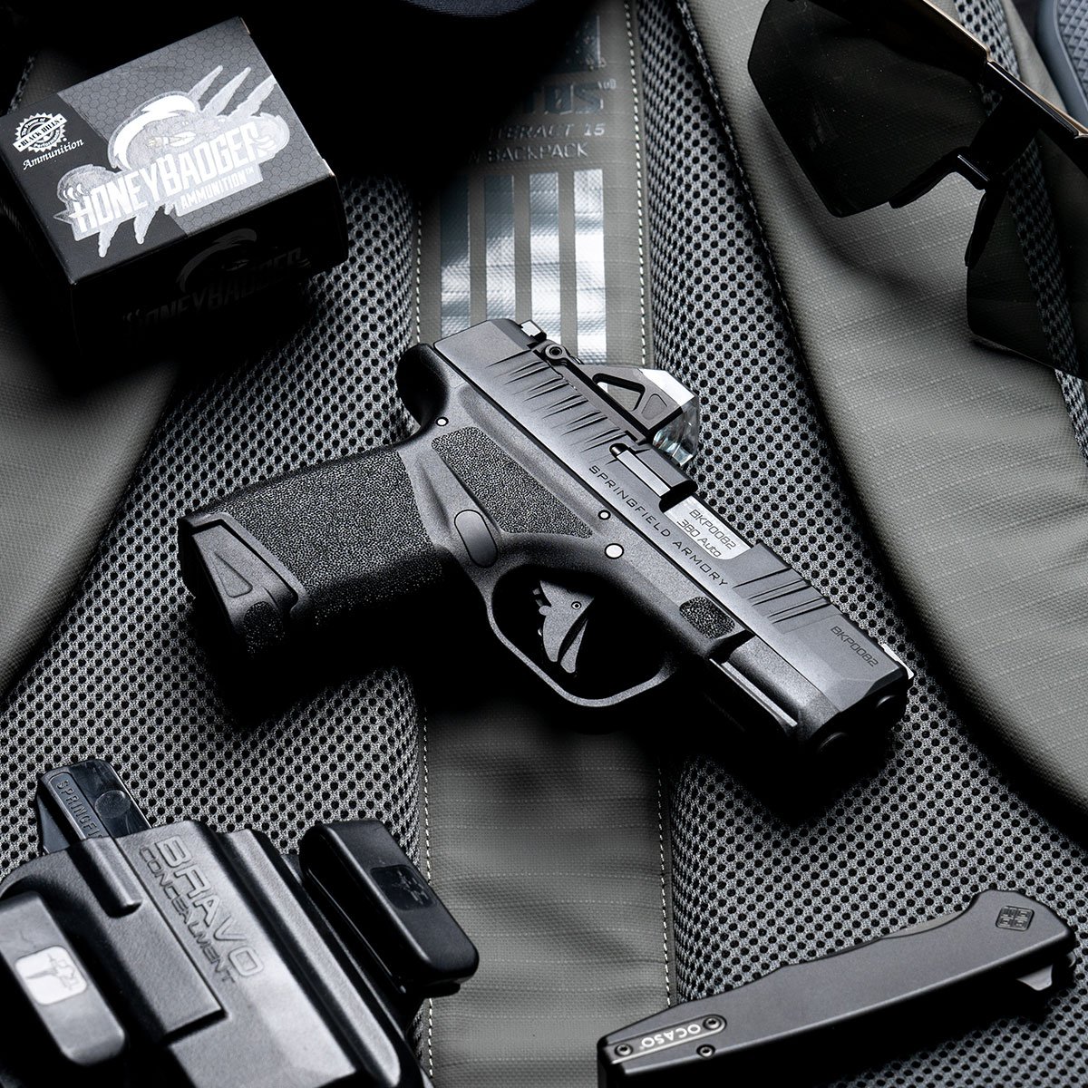 Pistola Springfield Armory Hellcat e carregadores organizados sobre bolsa preta.