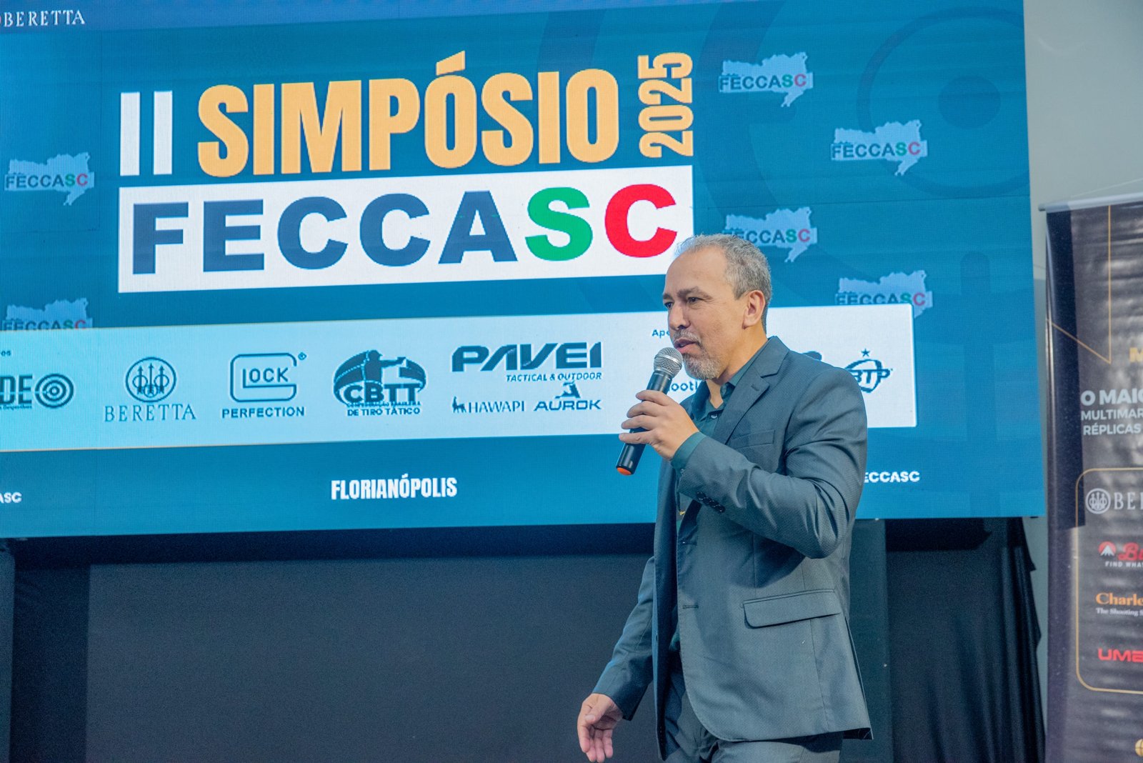 Homem de terno apresenta palestra no Simpósio FECCASC 2025.