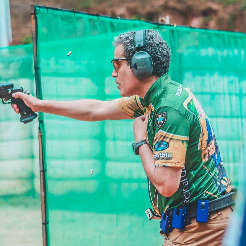 Demetrius Oliveira dispara pistola durante prova de tiro prático.