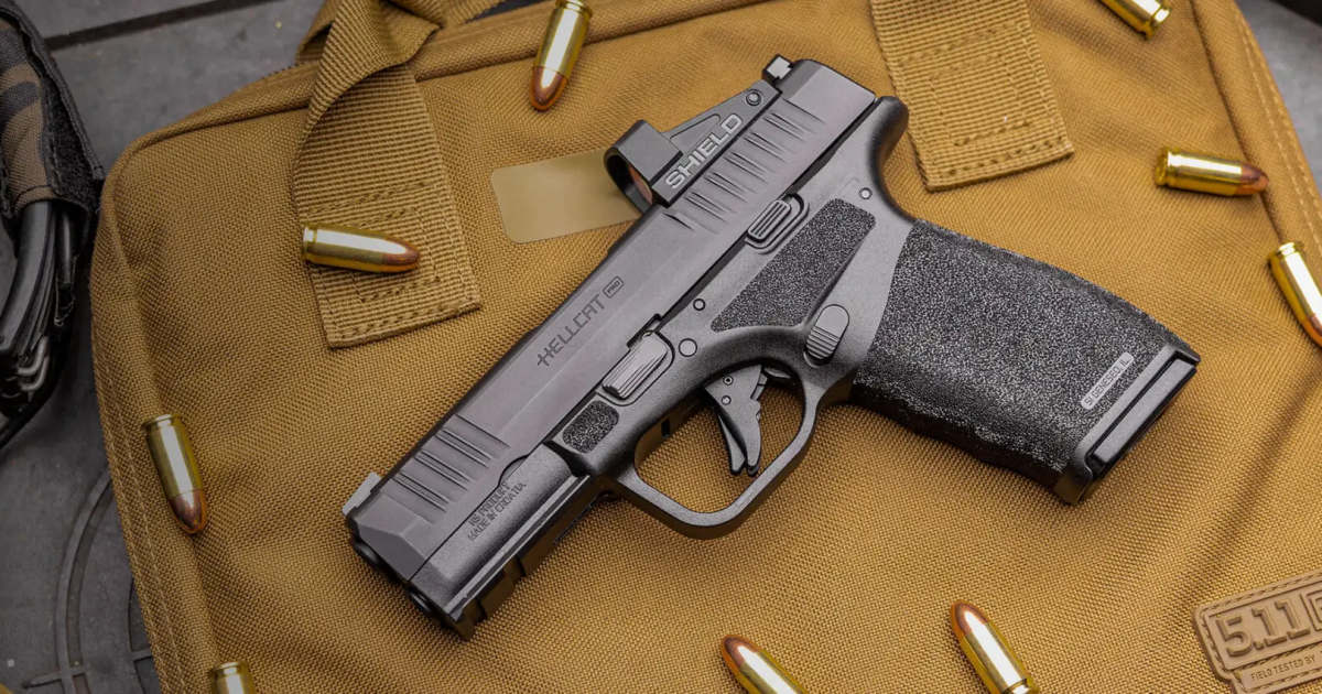 Pistola Hellcat Pro e cartuchos sobre uma bolsa tática marrom.