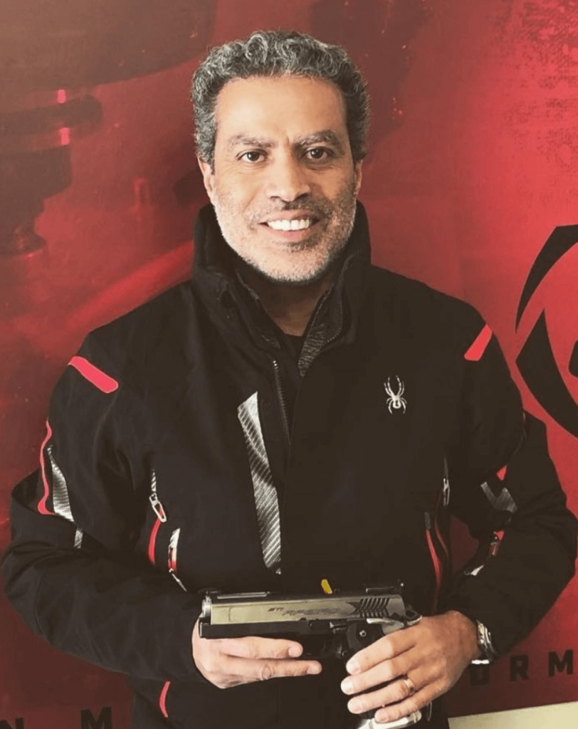Retrato de Demetrius Oliveira segurando uma pistola.