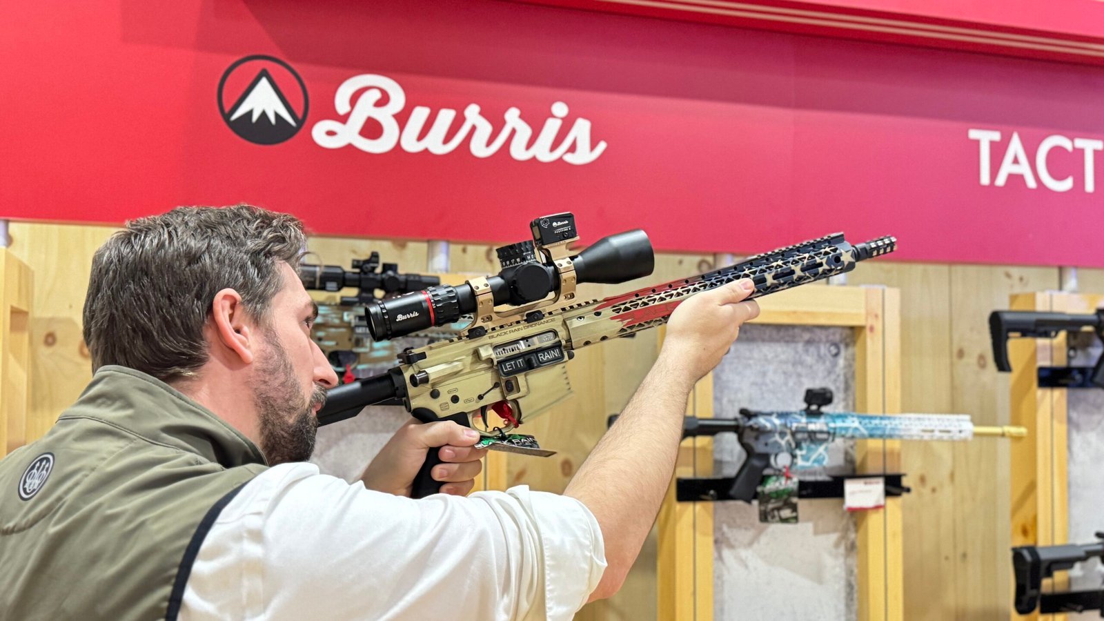 Visitante testa fuzil equipado com mira no estande da Burris.