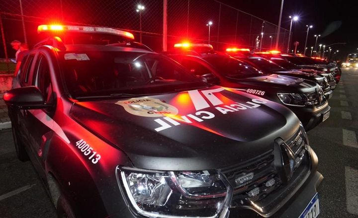 Viaturas da Polícia Civil com luzes vermelhas acesas durante operação noturna.