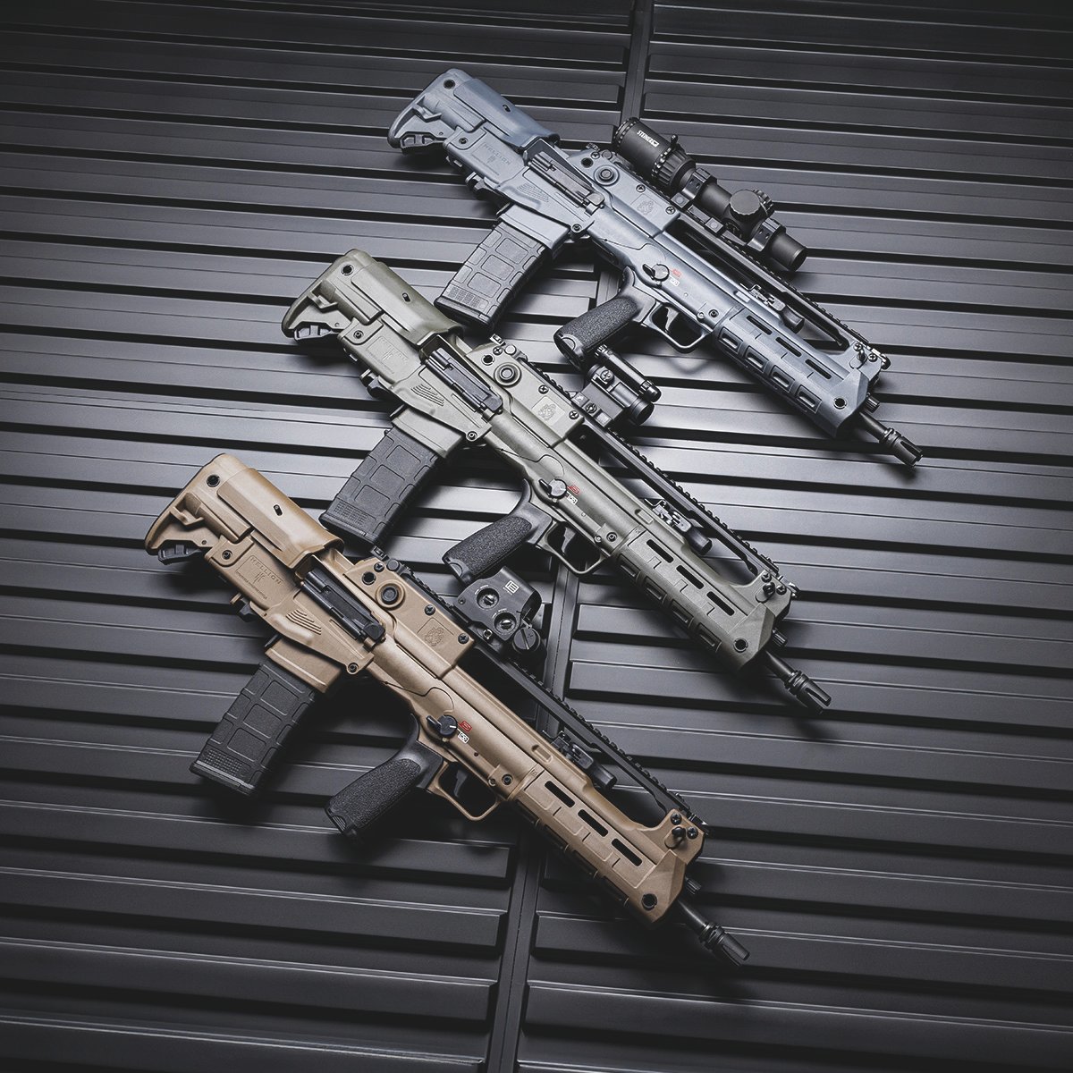 Três fuzis Springfield Armory Hellion em cores diferentes sobre painel preto.