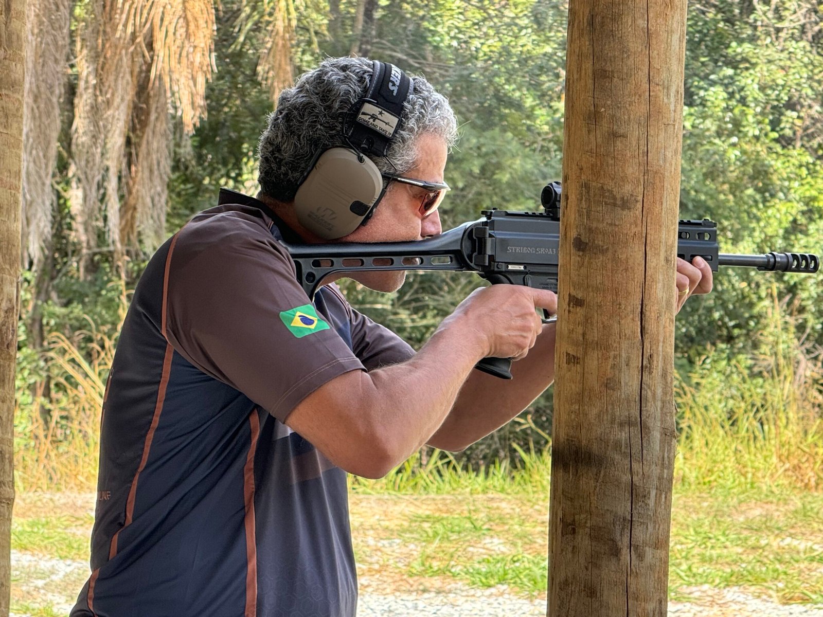Demetrius Oliveira dispara arma longa em campo de tiro ao ar livre.