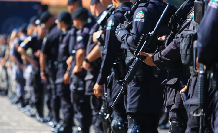 Policiais armados permanecem em formação.