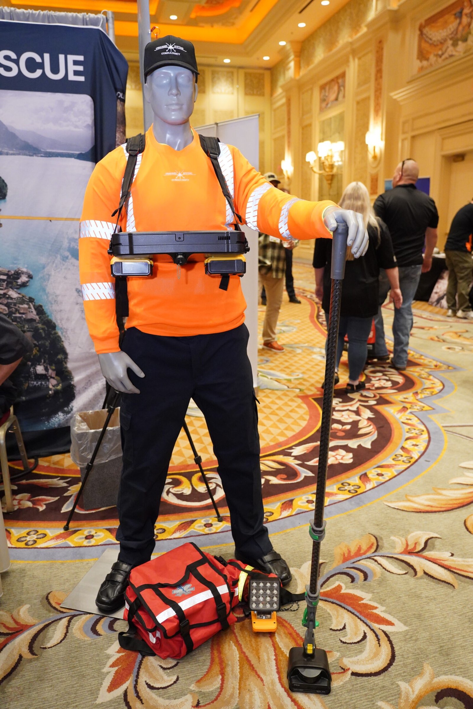 Manequim de resgate com uniforme laranja e equipamentos expostos.