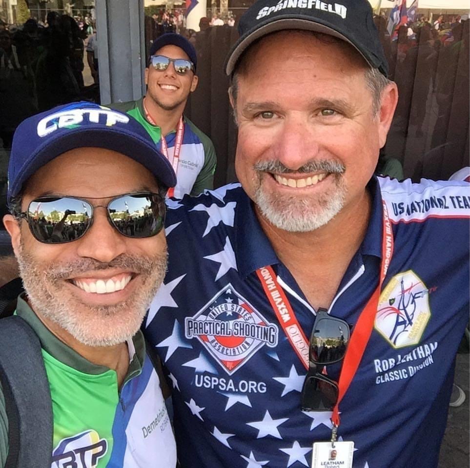 Demetrius Oliveira posa com atleta americano durante competição.