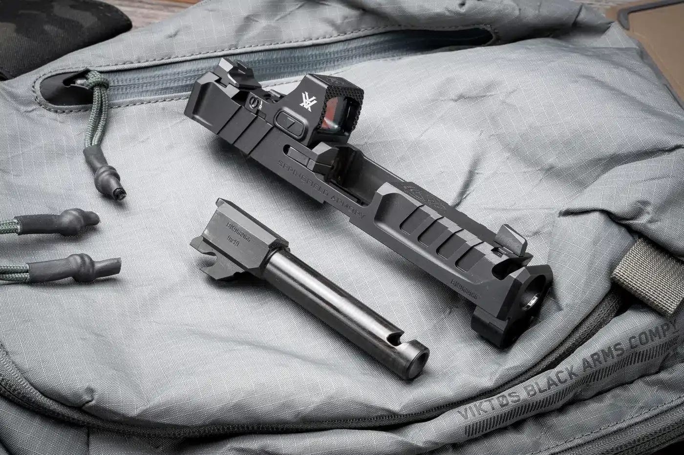 Ferrolho e cano desmontados da pistola Echelon 4.0C Comp sobre bolsa tática.