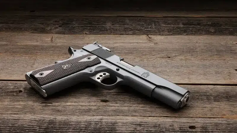 Pistola Springfield Armory 1911 Garrison Target apoiada sobre mesa de madeira.