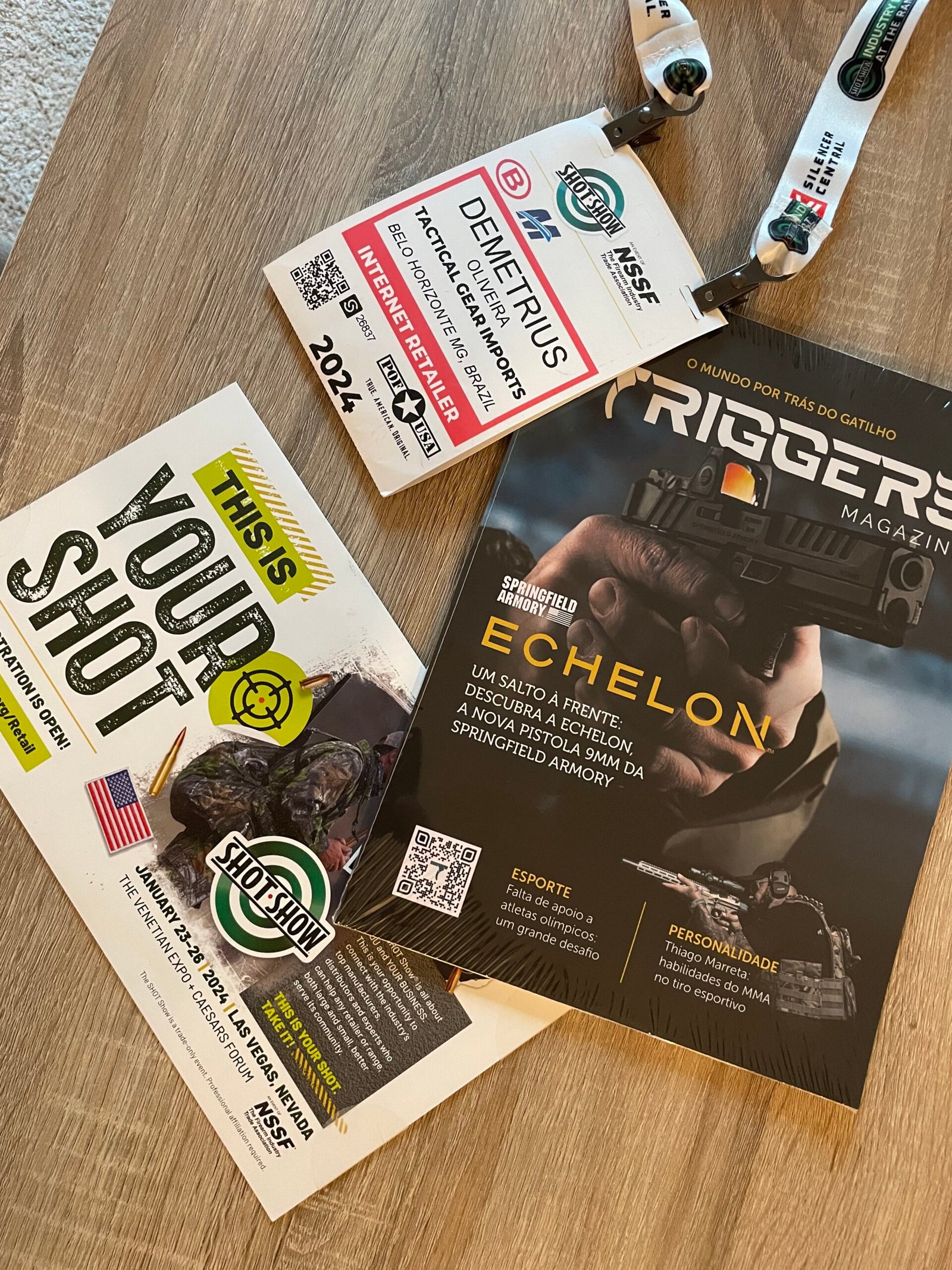 Credenciais e publicações da Triggers Magazine sobre uma mesa.