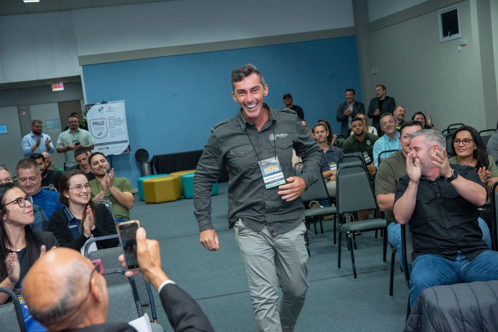 Participante recebe aplausos ao caminhar pelo auditório do Simpósio FECCASC.