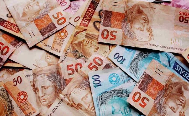 Cédulas de real espalhadas sobre uma superfície.