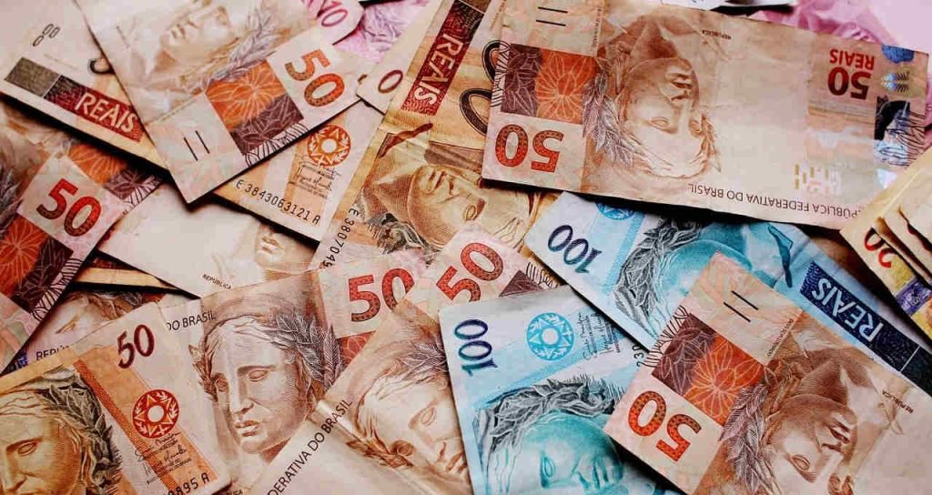 Cédulas de real espalhadas sobre uma superfície.