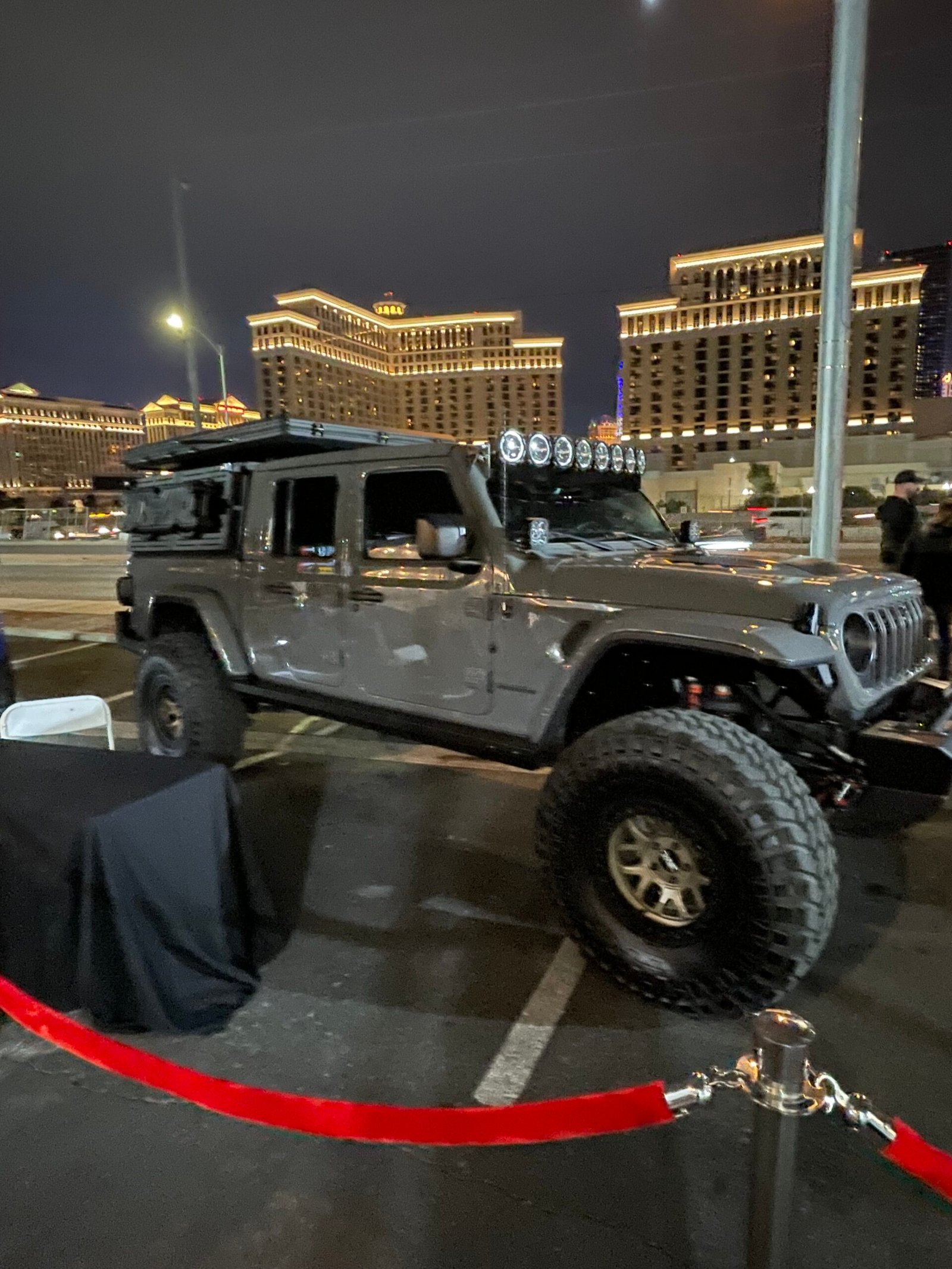 Veículo utilitário cinza com pneus grandes exposto à noite em Las Vegas.
