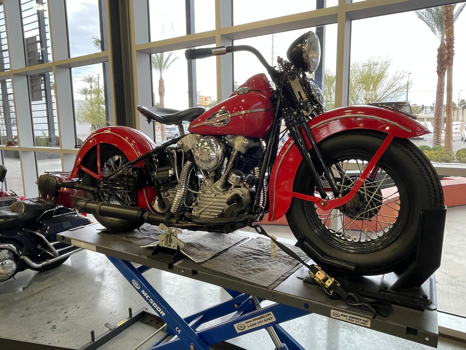 Motocicleta clássica vermelha exposta em plataforma.