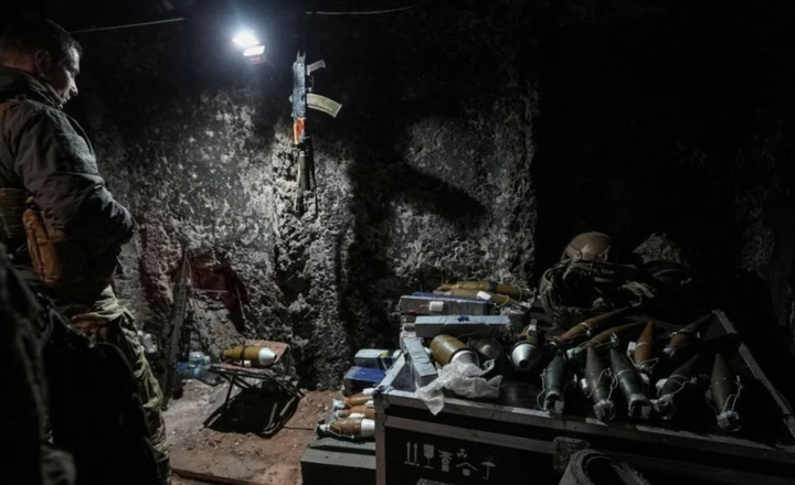 Militares trabalham com armamentos em uma posição escura de combate.