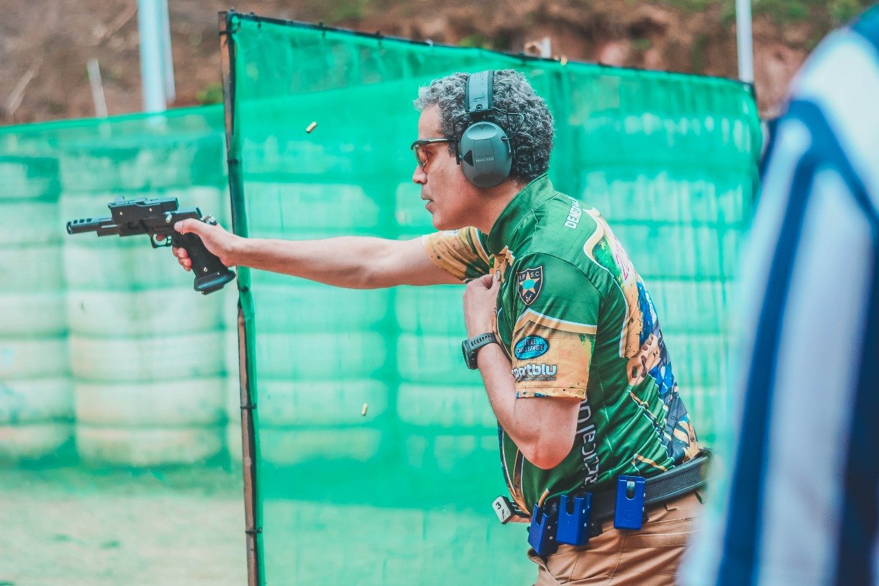 Demetrius Oliveira dispara pistola durante prova de tiro prático.