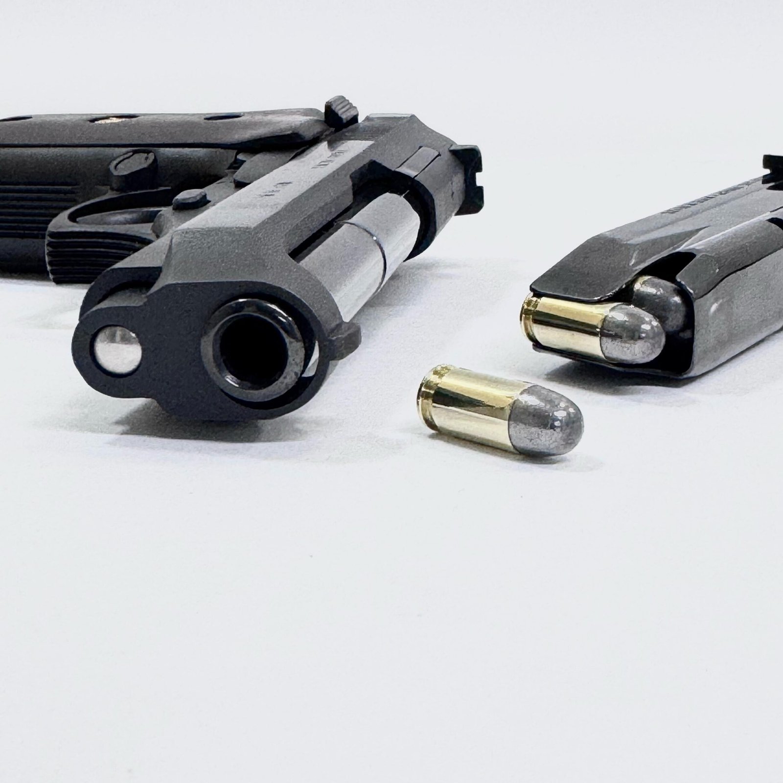 Pistola e carregadores com munição calibre .380 ACP sobre fundo branco.