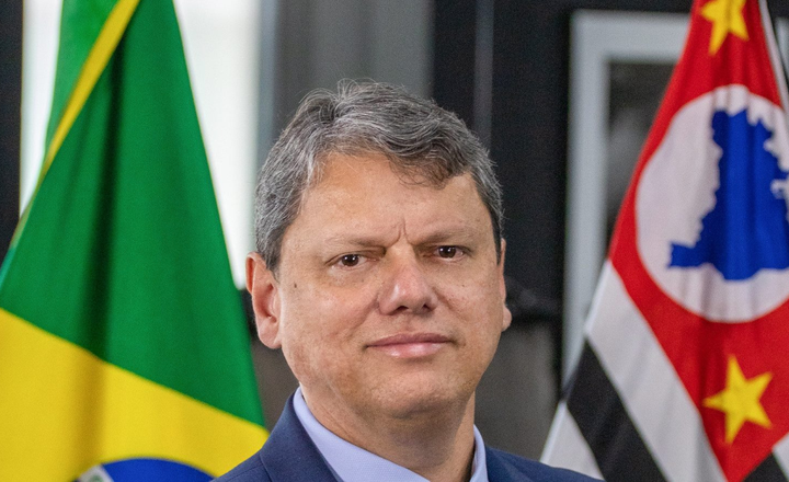 Governador Tarcísio de Freitas posa diante das bandeiras do Brasil e de São Paulo.